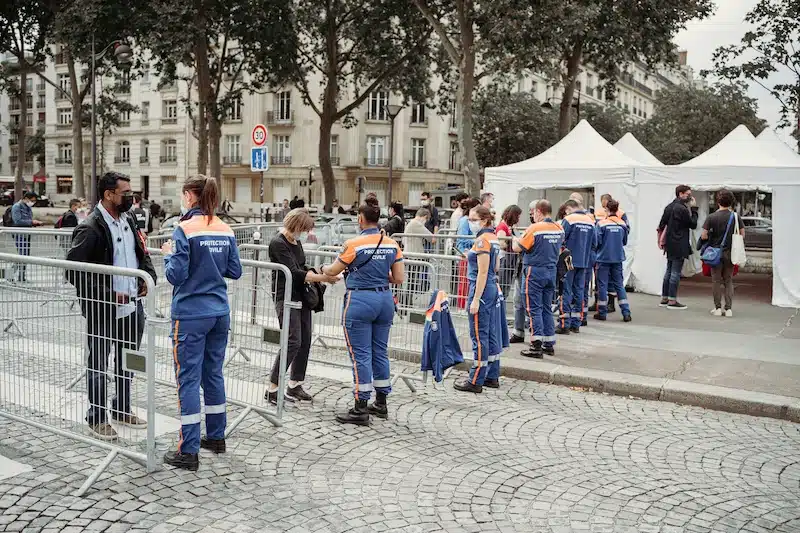 Protection civile à Paris avec passants et chapiteaux blancs, gestion de foule et dispositif de sécurité événementielle